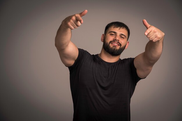 Sportive man in black shirt pointing someone. 