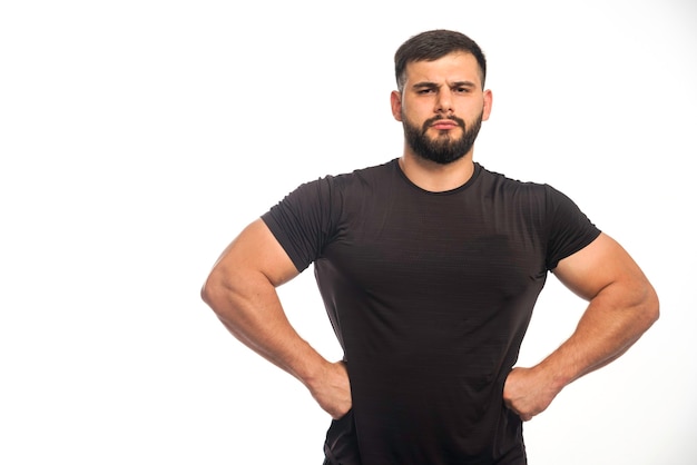 Free photo sportive man in black shirt putting his hand to his waist