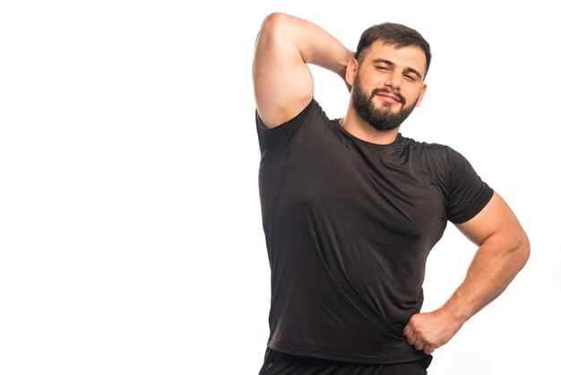 그의 삼두근 근육을 보여주는 검은 셔츠에 낚시를 좋아하는 남자.