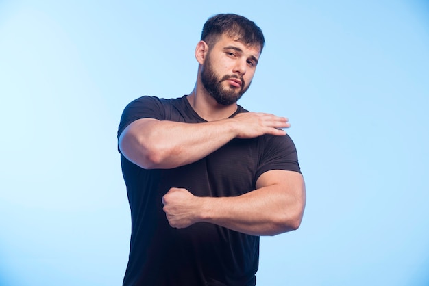 L'uomo sportivo in camicia nera mostra i suoi muscoli.