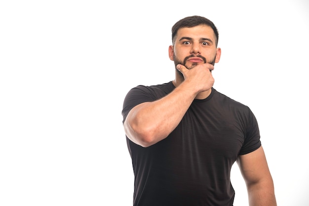 Free photo sportive man in black shirt touching his beard.