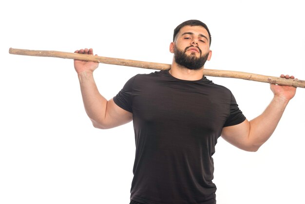 Sportive man holding a wooden kung fu stick