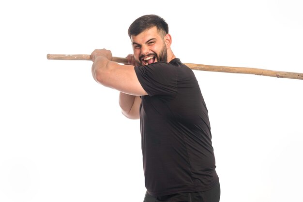 Sportive man holding a wooden kung fu stick