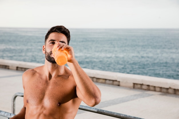 Sportive man hydration process after exercising