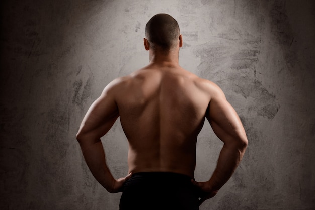  sportive man's body over dark wall.