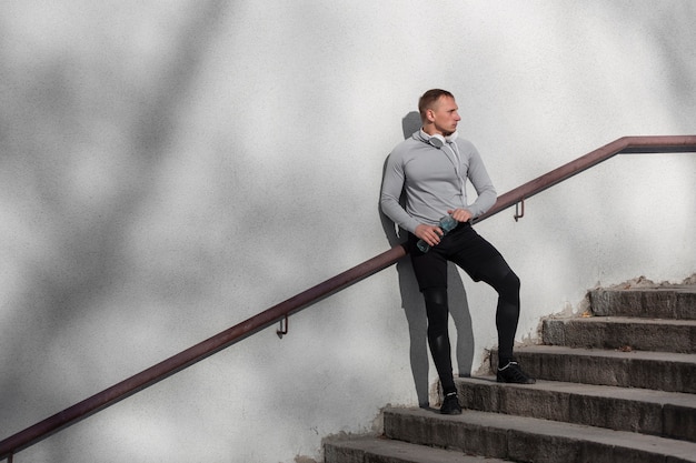 Foto gratuita uomo allegro che si siede sulle scale e che osserva via