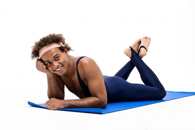 Sportive man smiling, lying on yoga mat