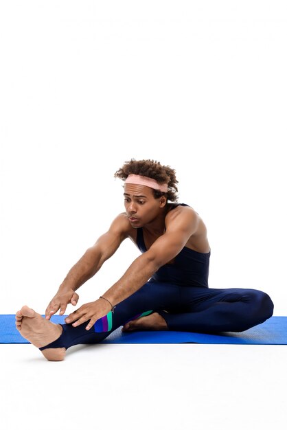 Sportive man stretching, sitting on yoga mat