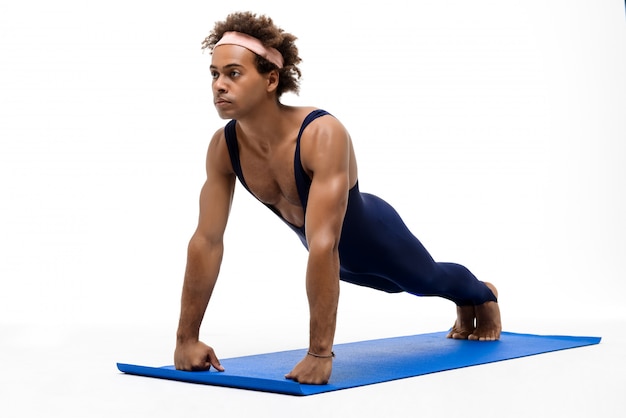 Sportive man training on yoga mat