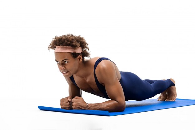 Sportive man training on yoga mat