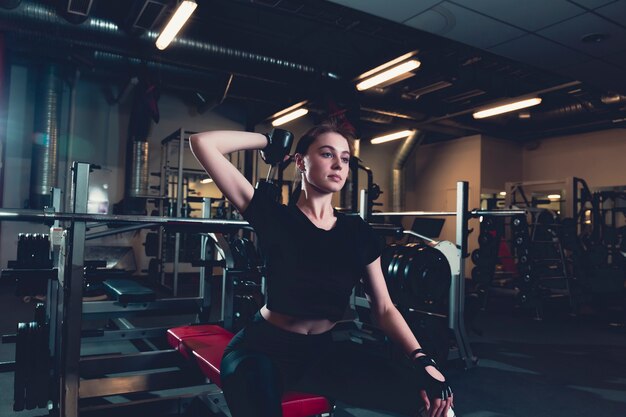 Спортивная молодая женщина делает упражнения с гантелями в фитнес-центре