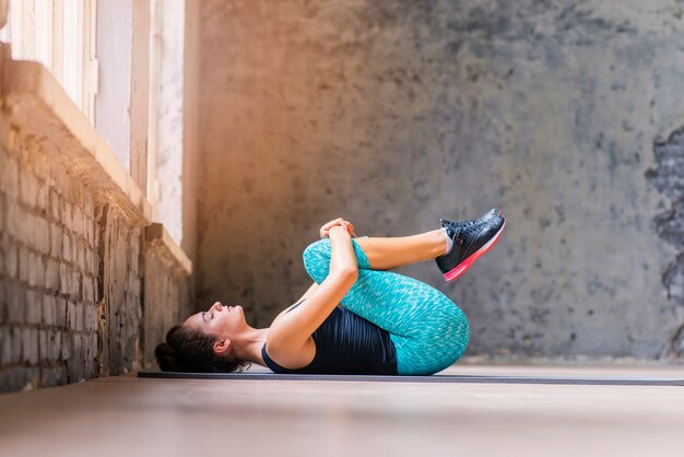 Sportive young woman exercising on yoga mat