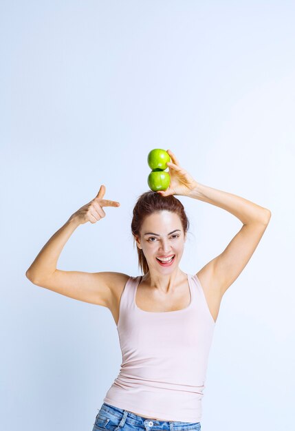 Спортивная молодая женщина, держащая зеленые яблоки над головой