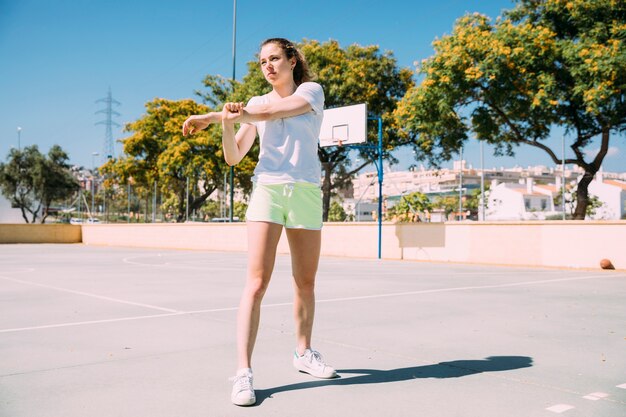 Sportive young woman warming up arms