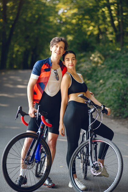 Sports couple riding bikes in summer forest