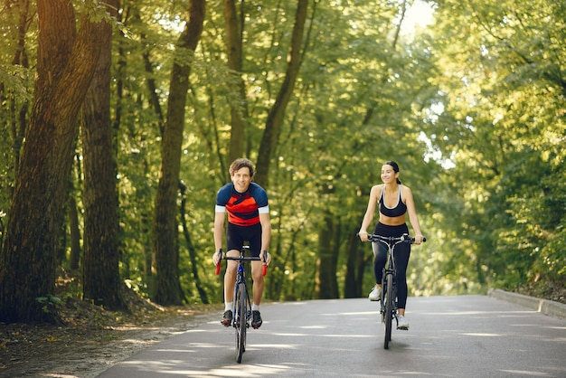 Sports couple riding bikes in summer forest