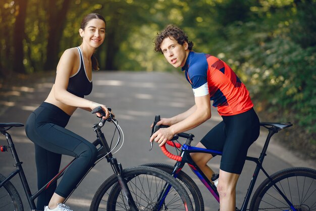 Sports couple riding bikes in summer forest