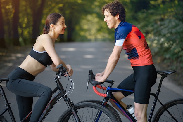 Sports couple riding bikes in summer forest