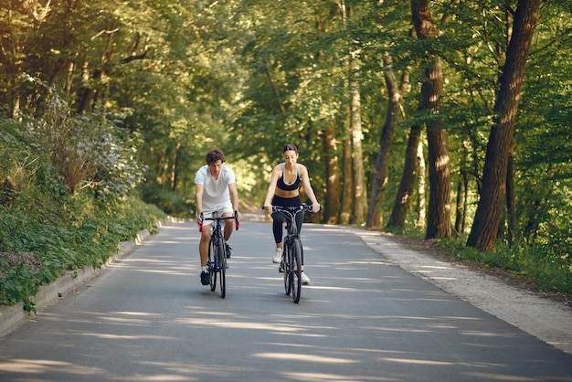Sports couple riding bikes in summer forest