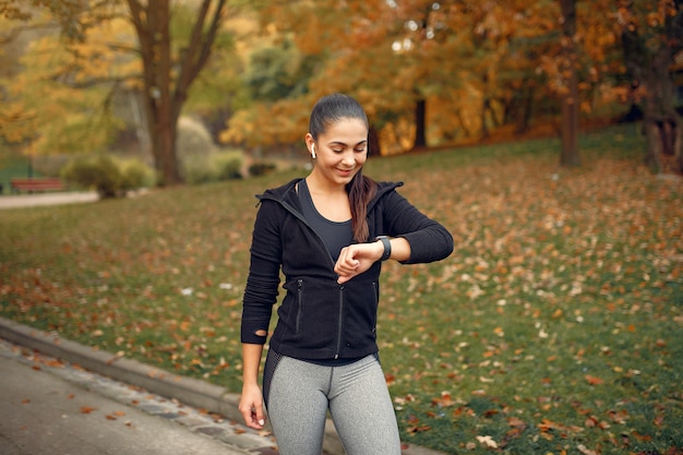 Sports girl in a black top training in a autumn park