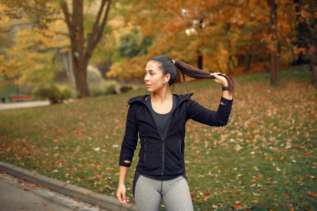 Sports girl in a black top training in a autumn park