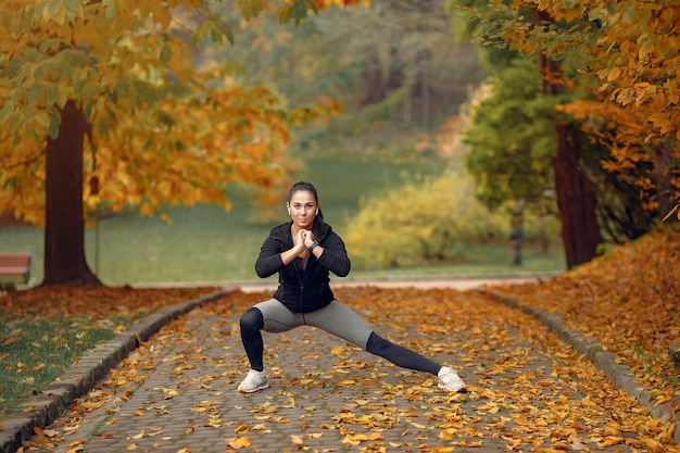 Mette in mostra la ragazza in un addestramento superiore nero in un parco di autunno