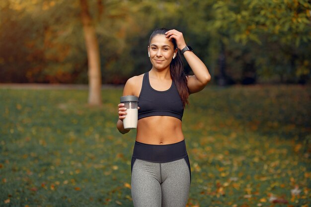 Sports girl in a black top training in a autumn park