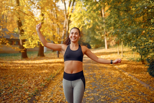 Sports girl in a black top training in a autumn park