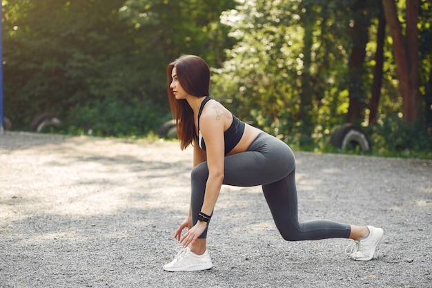 Sports girl in a black top training in a summer park