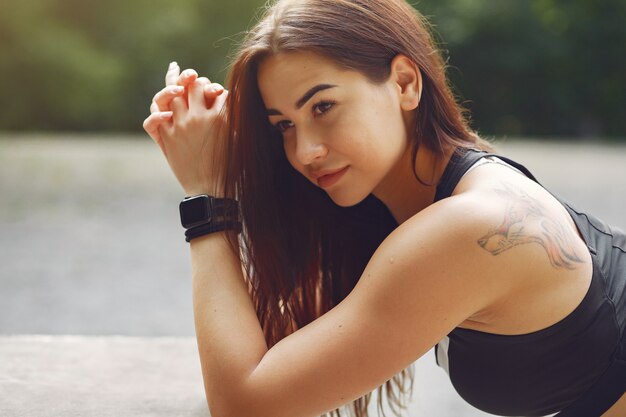 Sports girl in a black top training in a summer park