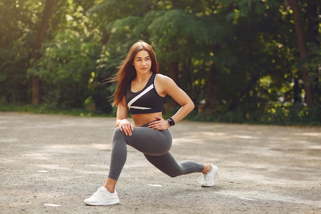 Sports girl in a black top training in a summer park