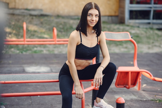 Sports girl in a black top training in a summer park