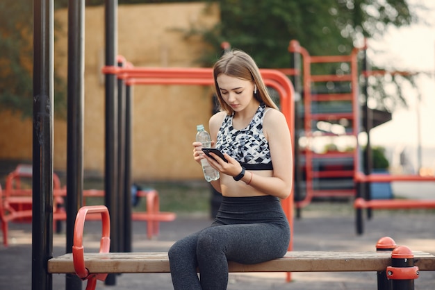 Sports girl in a black top training in a summer park