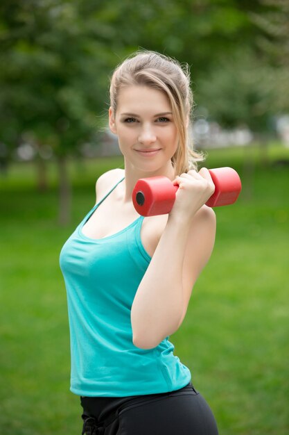 Sports girl exercise with dumbbells in the park