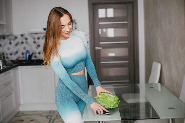 Ragazza sportiva in una cucina con verdure