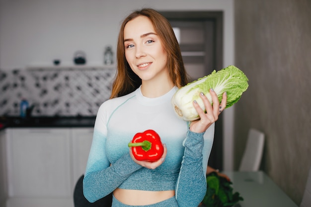 Sports girl in a kitchen with vegetables