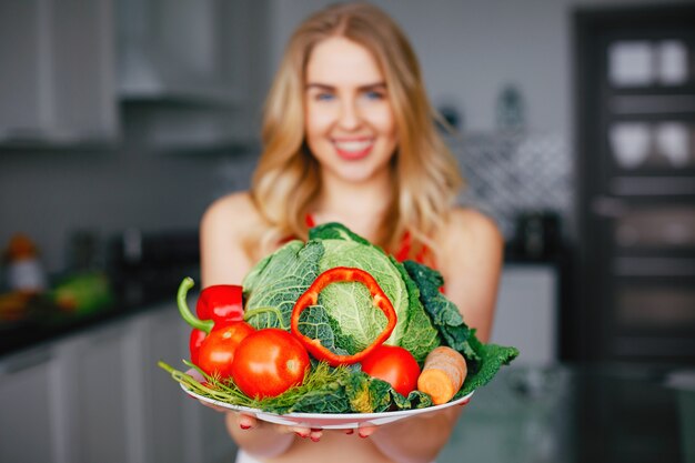 Sports girl in a kitchen with vegetables