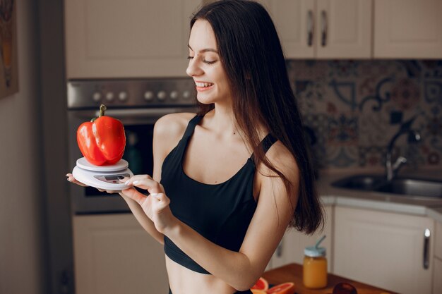 Sports girl in a kitchen with vegetables