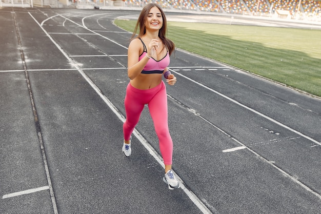 Спортивная девушка в розовой форме бежит по стадиону