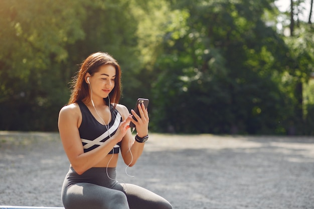 携帯電話とヘッドフォンでトレーニングスポーツ少女