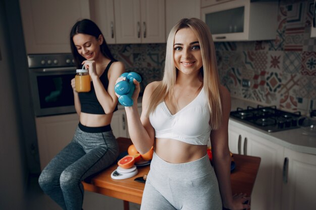 Sports girls in a kitchen with fruits