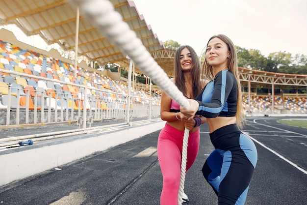 Спортивные девчонки в форме тренировки со скакалкой на стадионе