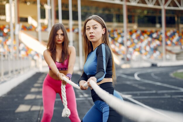 Спортивные девчонки в форме тренировки со скакалкой на стадионе