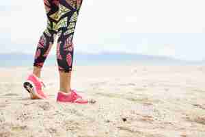 Free photo sports and healthy lifestyle concept. cropped shot of legs of girl athlete against ocean beach.