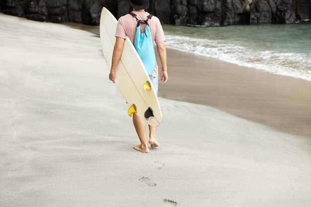 스포츠, 취미 및 건강한 라이프 스타일 개념. 바다 해안을 따라 걷는 젊은 맨발 남자의 뒷 모습