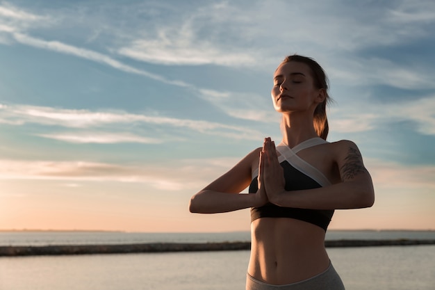 無料写真 ビーチでスポーツ女性は瞑想の練習をします。