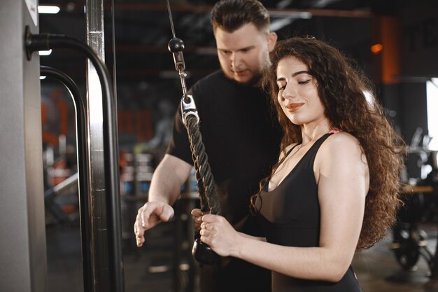 Sports woman in the gym. A man performs exercises. Guy in a t-shirt.