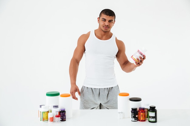 Sportsman holding vitamins and sport pills.