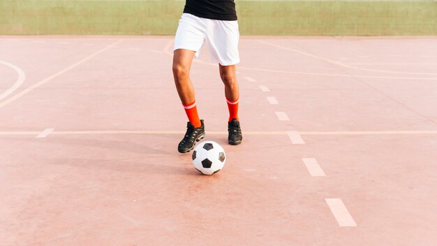 Спортсмен играет в футбол на спортивной площадке