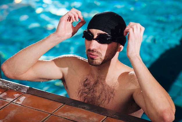 Sportsman putting on swimming goggles